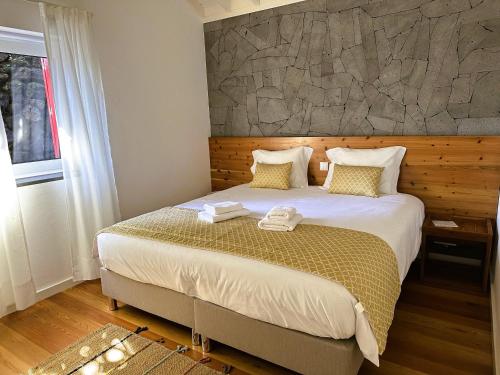 a bedroom with a large bed with a stone wall at Adega Baía Azul - The essence of Pico in São Roque do Pico