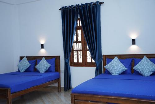 1 dormitorio con 2 camas y ventana en Hotel Theevanni Inn en Trincomalee