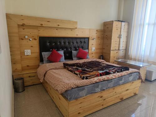 a bedroom with a large wooden bed with red pillows at Uk09 hotel & Restaurant in Mussoorie