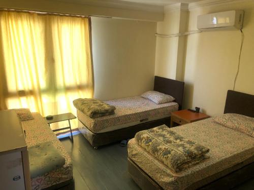 Cette chambre comprend 3 lits et une fenêtre. dans l'établissement DİZLEK PANSİYON, à Antalya