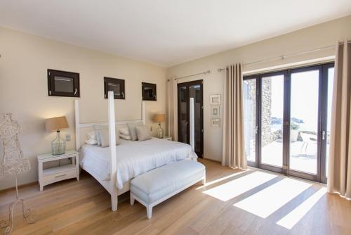 a white bedroom with a bed and a window at Endorikles Villa in Super Paradise Beach