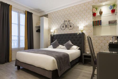 a bedroom with a bed and a desk with a bike on the wall at Résidence du Pré in Paris