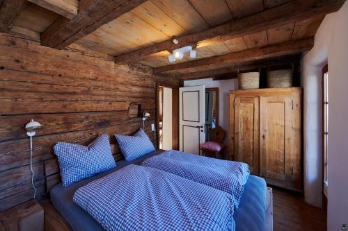 1 dormitorio con 1 cama azul y paredes de madera en Zum Seifensieder, en Brixen im Thale
