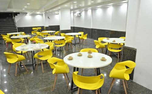 Hotel Down Town Paschim Vihar في نيودلهي: غرفة بها طاولات وكراسي صفراء
