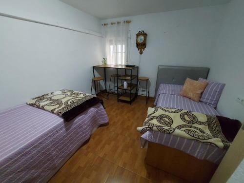 コルドバにあるApartamento acogedor Córdobaのベッドルーム1室(ベッド2台、壁掛け時計付)