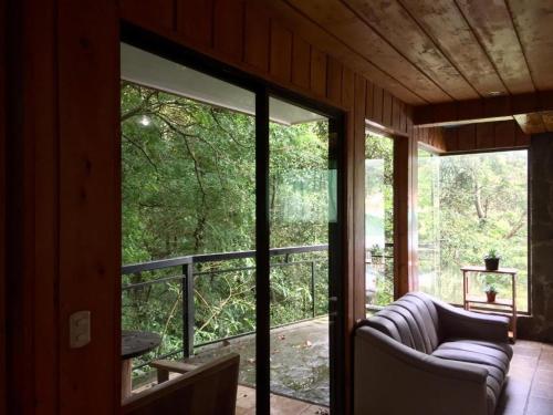 a screened in porch with a couch and a window at Manakin Lodge, Monteverde in Monteverde Costa Rica