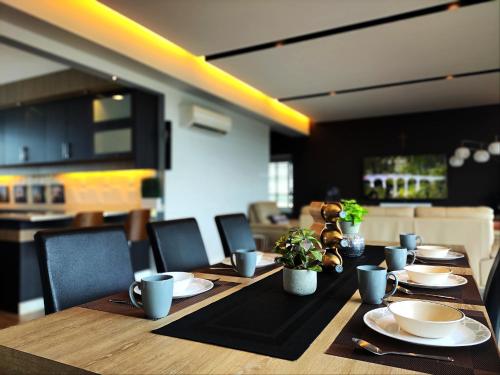 a long wooden table with plates and cups and plants on it at Bright Cozy 3 Bedrooms in Sibu