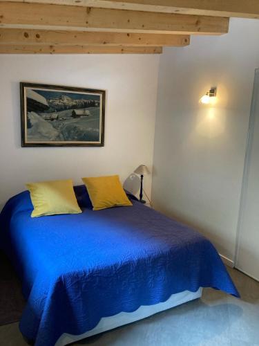 - un lit bleu avec 2 oreillers jaunes dans une chambre dans l'établissement Meridies, à Plateau dʼAssy