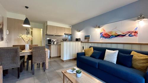 a living room with a blue couch and a kitchen at Argousiers 21 in Fort-Mahon-Plage
