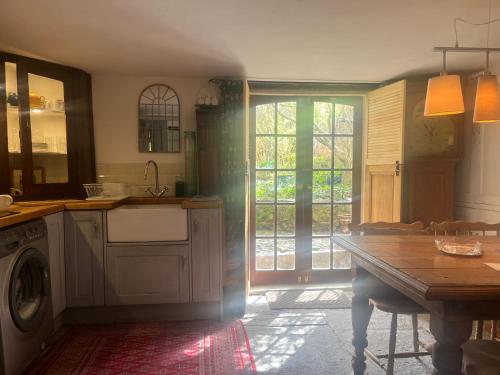a kitchen with a table and a washing machine at French Gite Style Garden Apartment, Central Taunton in Taunton