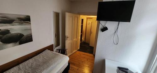 a room with a bed and a television on a wall at Balthasar Neumann Speiserei & Gästehaus - Zentrum Brühl -E-Ladestation, nähe Phantasialand in Brühl