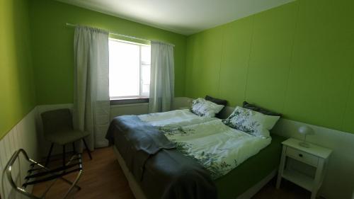 una camera verde con un letto e una finestra di Fornilækur Guesthouse a Blönduós