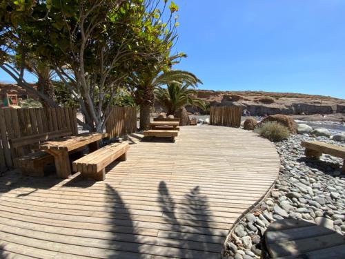 een houten loopbrug met banken en bomen op het strand bij Apartamento Sara in Santa Cruz de Tenerife