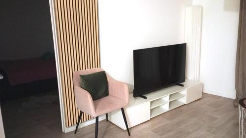 sala de estar con silla y TV en Appartement aux portes de Paris, en Villeneuve-la-Garenne