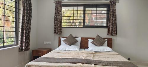 a bedroom with a bed and two windows at Sugamya Farm Guesthouse in Sāgar
