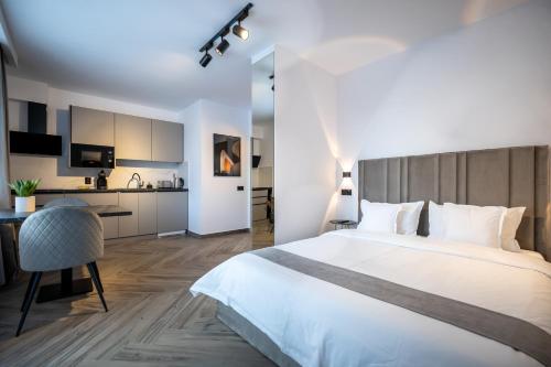 a bedroom with a large white bed and a kitchen at Urbio Private Suites in Cluj-Napoca