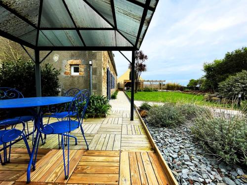 a wooden deck with a blue table and chairs on it at Maison Les Agapanthes in Lanmodez