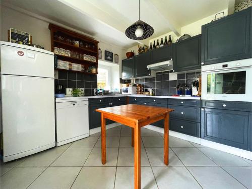 a kitchen with blue cabinets and a wooden table at Maison Les Agapanthes. in Lanmodez