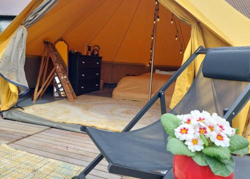 uma tenda com uma cama e uma cadeira com flores em Glamping Hoeve Thenaers em Gingelom