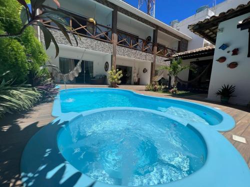 a large blue pool in front of a house at Villa Bangalu in Porto De Galinhas