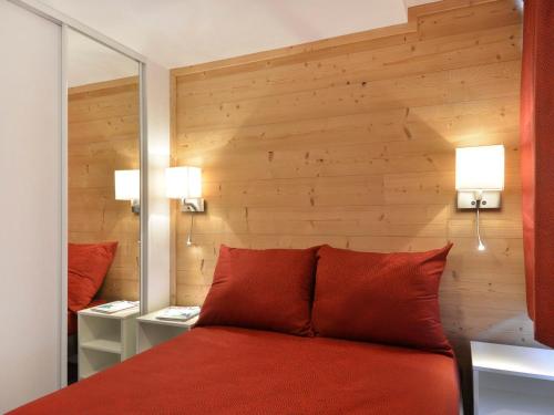 a bedroom with a red bed with two lamps and a mirror at Appartement Plagne Bellecôte, 3 pièces, 7 personnes - FR-1-181-1937 in La Plagne Tarentaise
