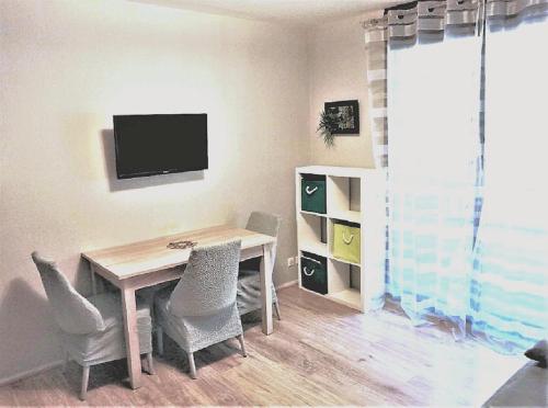 une salle à manger avec une table, des chaises et une télévision dans l'établissement Charmant T2, hypercentre, calme, terrasse, parking, à Luchon