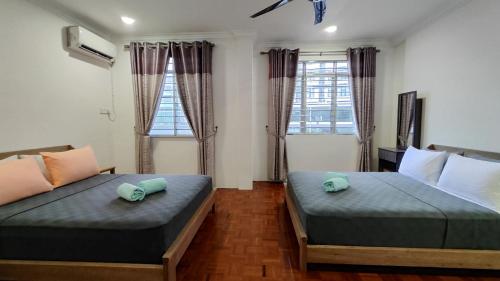 two beds in a room with two windows at Sibu T2 Homestay, 4 Bedrooms in Sibu