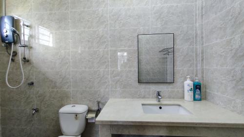 a bathroom with a toilet and a sink and a mirror at Sibu T2 Homestay, 4 Bedrooms in Sibu