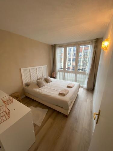 a bedroom with a bed and a large window at Appartement Moderne 2 chambres Proche Paris in Meudon