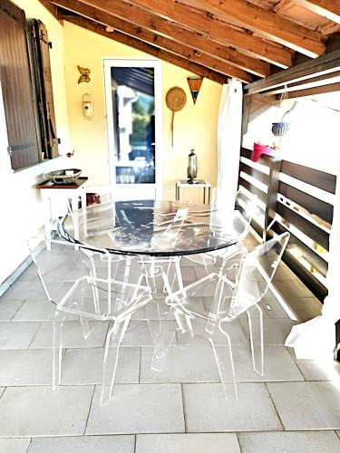 a glass table and chairs on a patio at Maison paisible à Veyras avec piscine privée et vue montagne in Veyras