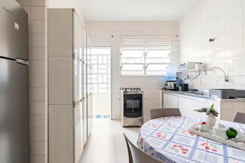 a white kitchen with a table and a refrigerator at Amplo apartamento Barra Salvador in Salvador