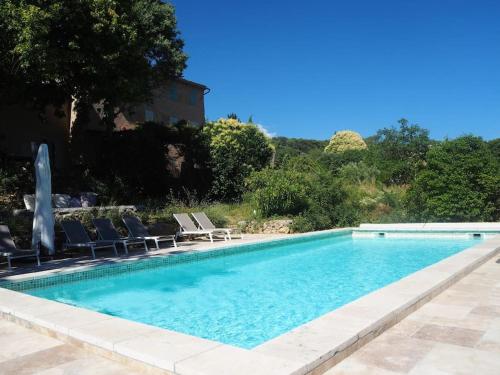 une piscine avec des chaises et une fontaine dans l'établissement Villa avec piscine, boulodrome, yoga, grand jardin, à Cotignac