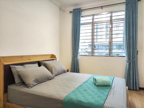 a bedroom with a bed with blue curtains and a window at Sibu T1 Homestay, 4 Bedrooms in Sibu