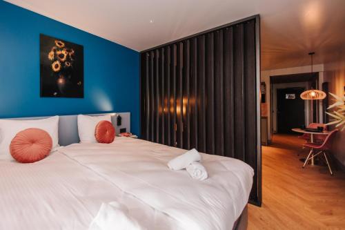 a bedroom with a large white bed with blue walls at Hotel Keur in Zandvoort