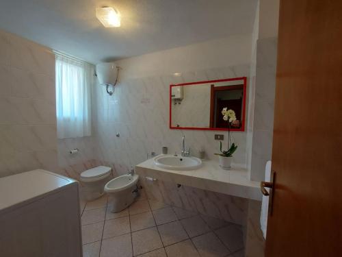 Baño blanco con aseo y lavamanos en Villa Gio' Iun R4245, en Sinnai