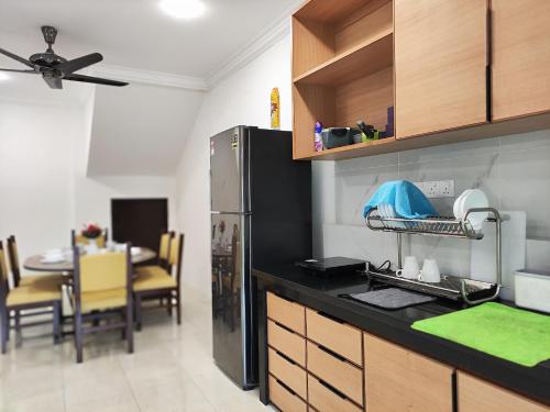 a kitchen with a refrigerator and a table with chairs at Sibu T1 Homestay, 4 Bedrooms in Sibu