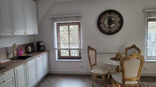 eine Küche mit einem Tisch und Stühlen sowie einer Uhr an der Wand in der Unterkunft APARTAMENT JARACZA 28/15 in Słupsk