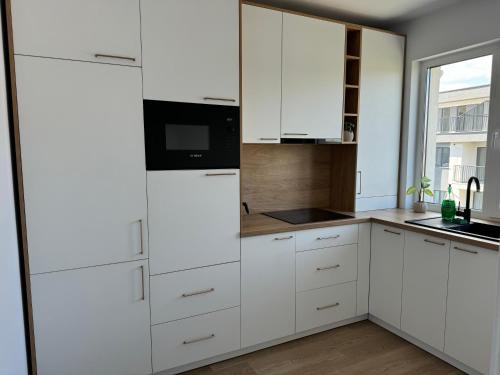 uma cozinha branca com armários brancos e uma janela em Modern și confortabil em Floresti
