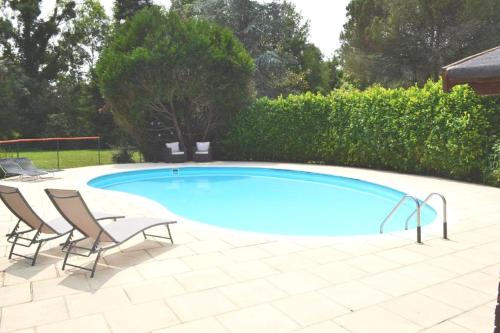 a swimming pool with two chairs and a table at Les Bruyeres B&B in Montbron