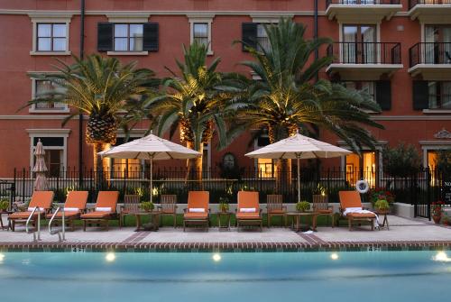 a pool with chairs and umbrellas in front of a building at Hotel Granduca Houston in Houston