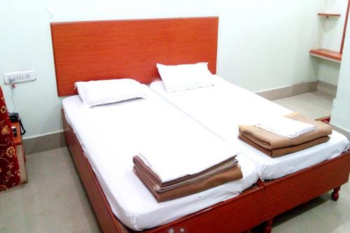 1 cama con sábanas blancas y cabecero de madera en Hotel Kashi Inn Varanasi By GRG, en Varanasi