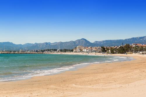 a beach with the ocean and mountains in the background at Camping La Torre del Sol - Maeva Vacansoleil in Miami Platja
