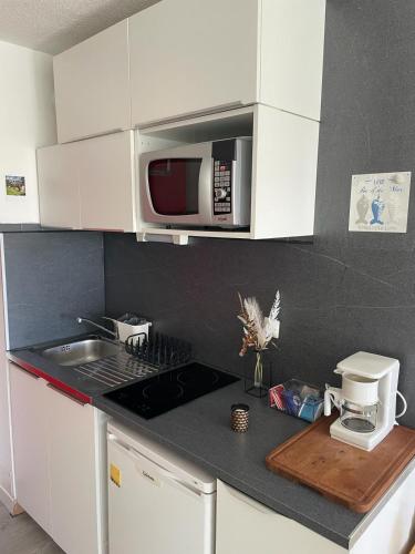 une cuisine avec un évier et un micro-ondes dans l'établissement Le Nid d'Eden, à La Grande Motte