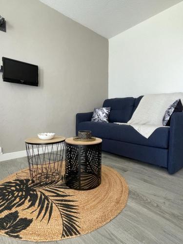 un salon avec un canapé bleu et deux tables dans l'établissement Le Nid d'Eden, à La Grande Motte