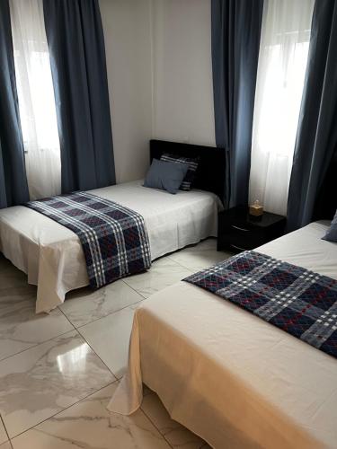a bedroom with two beds and two windows at Pensão Gonçalves in Calheta