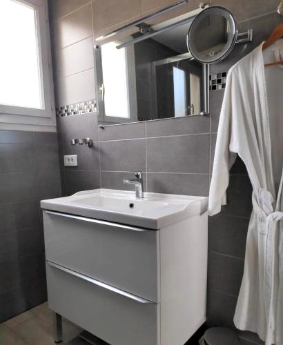 une salle de bain avec un lavabo blanc et un miroir dans l'établissement Appartement moderne à Uzès, 70 m², proche centre-ville, à Uzès