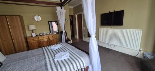 a bedroom with a bed with curtains and a tv at The Holmlea in Blackpool