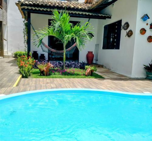 a blue swimming pool in front of a house at Villa Bangalu Exclusiva para Adultos in Porto De Galinhas