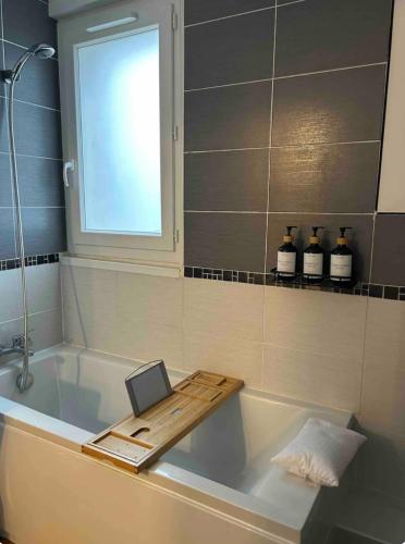 a bathroom with a bath tub with a laptop on it at Escapade Cinéma : Duplex 50m² in Linas