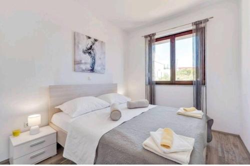 a white bedroom with two beds and a window at HOLIDAY HOME LUANA in Maslenica